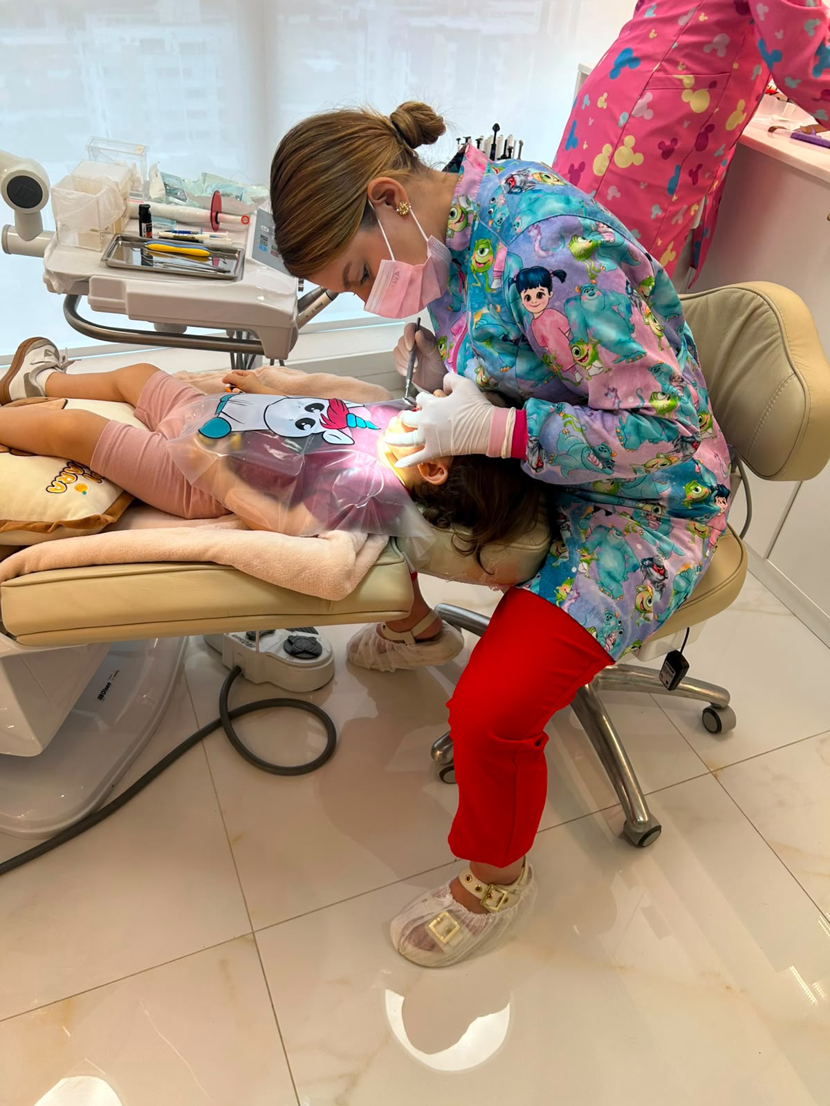 Dra. Thirza Nunes realizando atendimento em criança com avental ilustrado